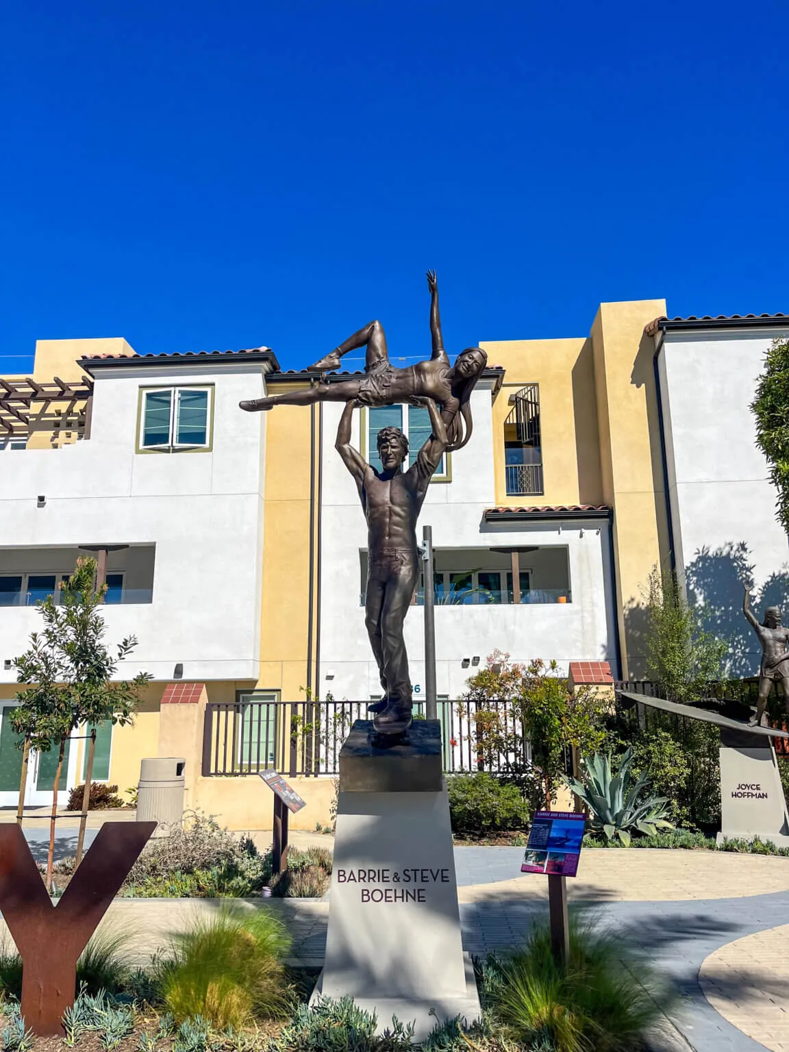 Bronze statue of tandem surfers, one lifting the other overhead